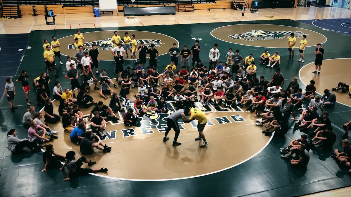 Campers gathered around a technique demonstration on the mat at Mustang Wrestling Camp